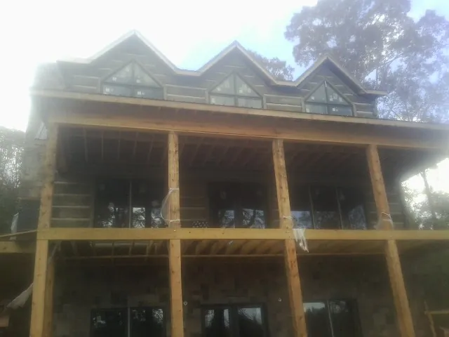Dormers and porch framing on a large log home under construction — Roof Coating work by our crew in Nelsonville